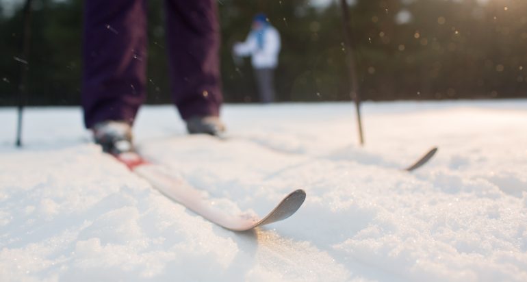 Skis on skier feet standing on snowdrift during physical activity on wintery day